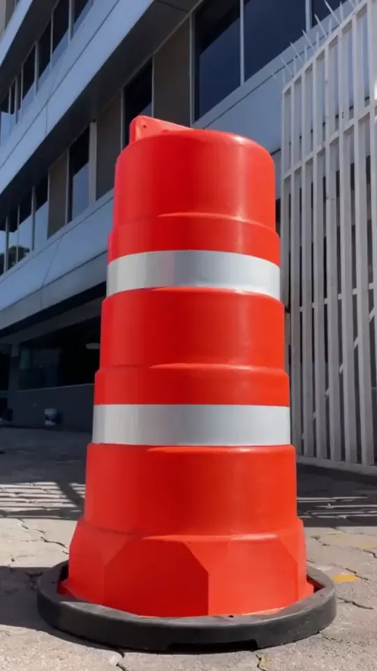 Trafitambo Shark naranja con dos reflejantes sobre su base, en la banqueta frente a un edificio
